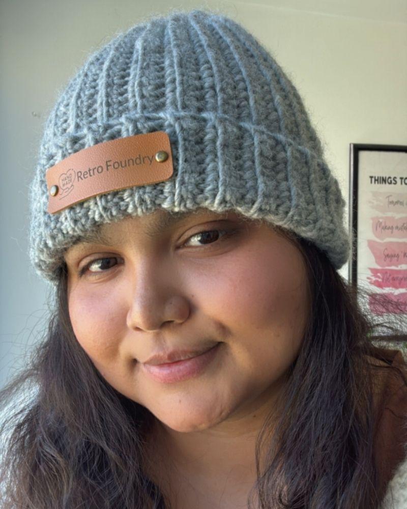 Person wearing a handmade beanie with a leather patch labeled 'Retro Foundry', Gray