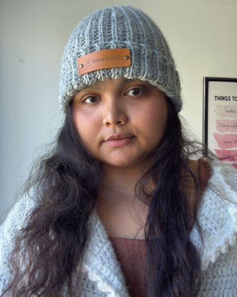 Person wearing a handmade beanie with a leather patch labeled 'Retro Foundry', Gray