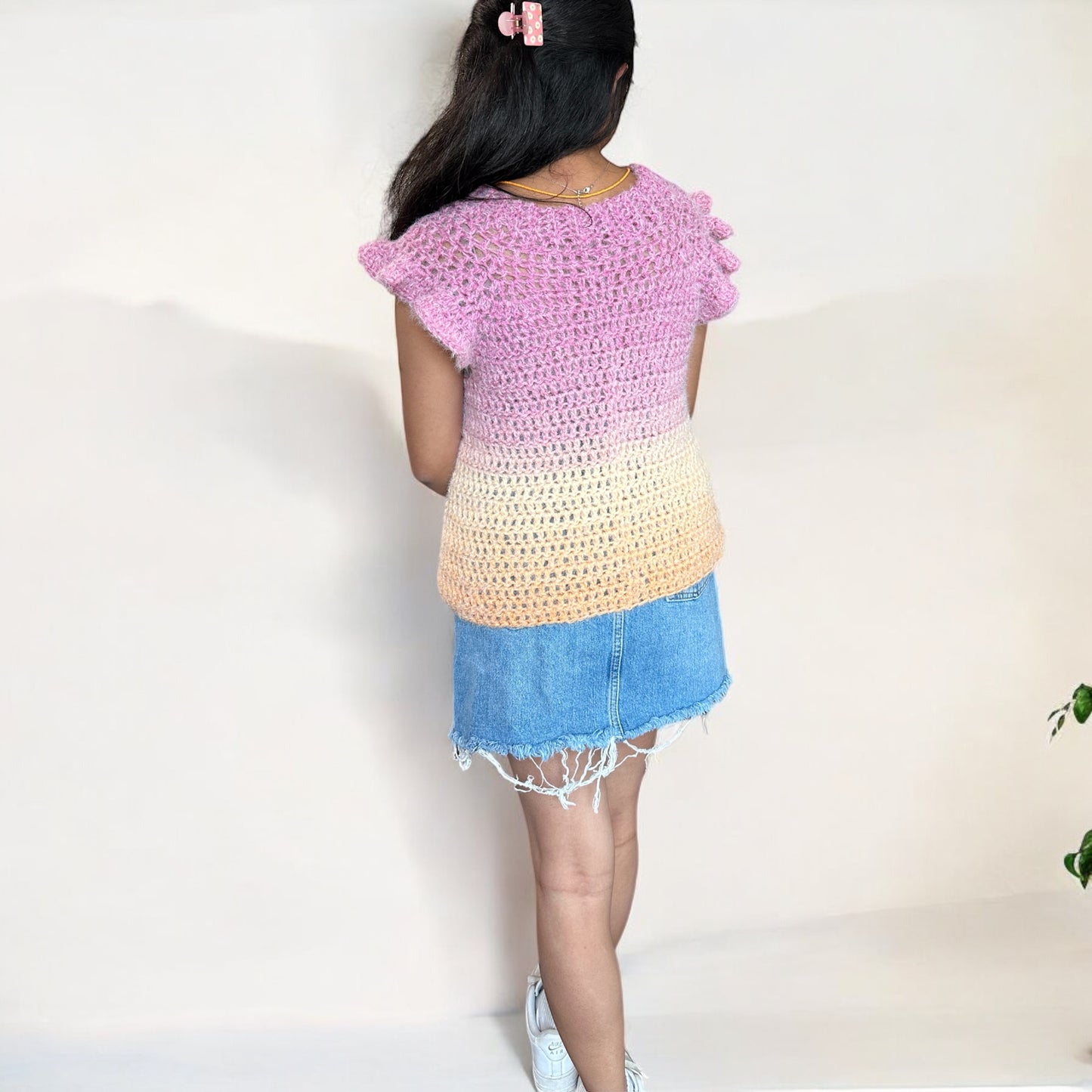 A girl wearing a crochet top-down blouse, showcasing the back design and stitch details.