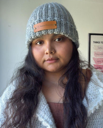 Person wearing a handmade beanie with a leather patch labeled 'Retro Foundry', Gray