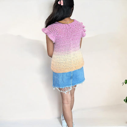 A girl wearing a crochet top-down blouse, showcasing the back design and stitch details.